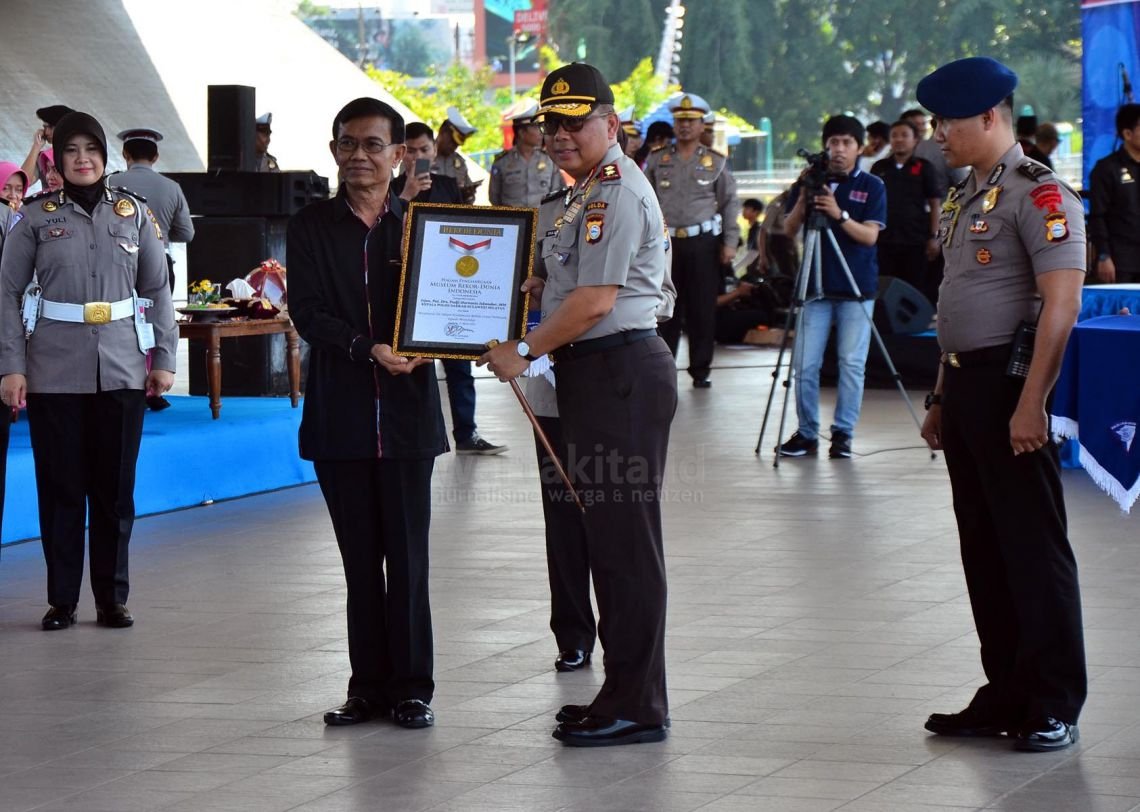 Kapolda Sulsel Irjen Pol Pudji Hartanto (kanan) menerima penghargaan dari Museum Rekor Indonesia (MURI) dalam acara Apel Besar Pelopor Keselamatan Berlalu Lintas di Lapangan Karebosi, Makassar, 21 Maret 2016.