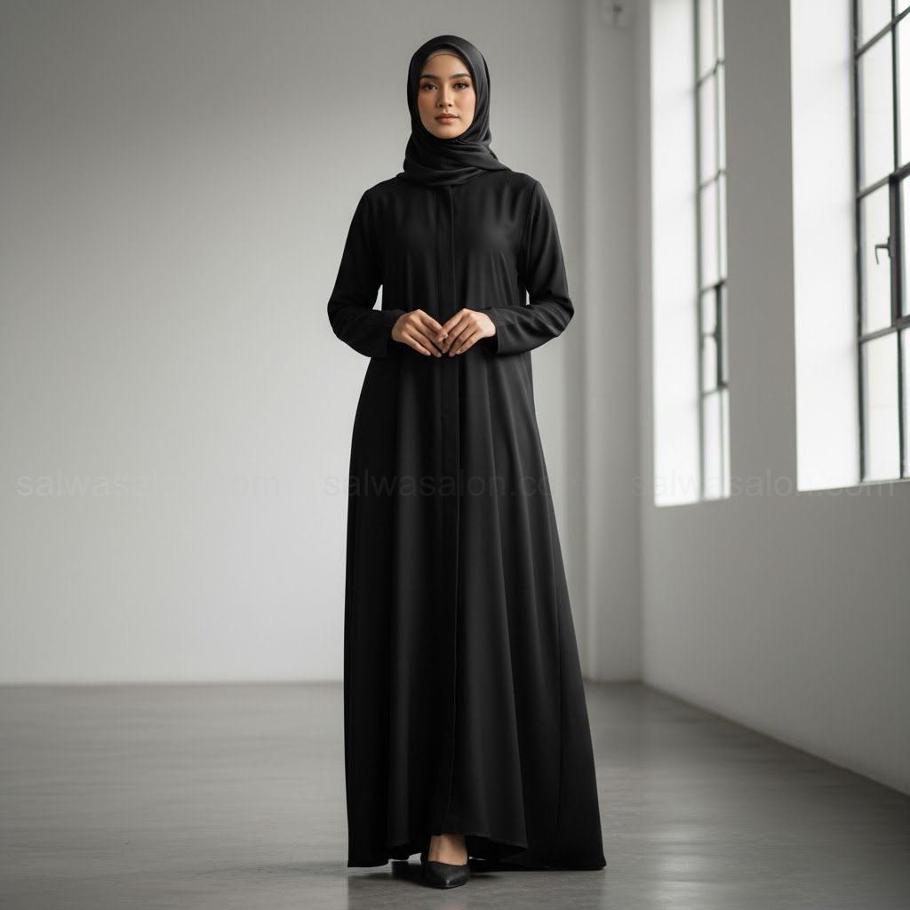 Seorang wanita Muslim Indonesia yang sangat elegan mengenakan 'abaya modern' berwarna hitam pekat (jet black). Potongannya lurus, simpel, tanpa ornamen, terbuat dari bahan premium yang jatuhnya mewah.