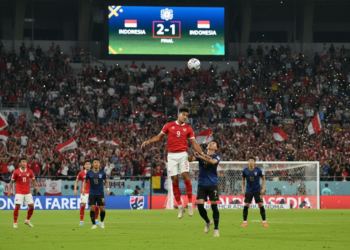 A high-energy soccer match between Indonesia and Thailand at the final of FIFA ASEAN Cup 2026, with players in action, fans cheering, and the Gelora Bung Karno stadium in the background, reflecting the tension and excitement of the moment.