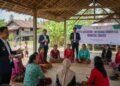 Bapas Makassar's team, led by Budi S., is conducting a community integration workshop in Marusu, Maros. The team is interacting with local community members in a traditional village setting, with a fe