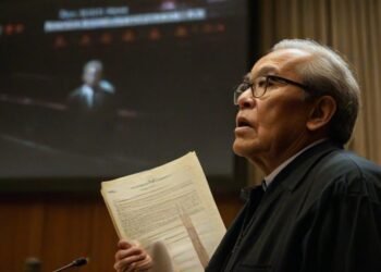 Politisi MA. Untung berdiri di depan layar besar yang menampilkan logo Mahkamah Konstitusi. Dia mengepal dokumen dan tampak serius dengan ekspresi yang memikirkan. Latar belakang menunjukkan ruang par