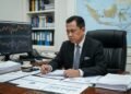 Galeri Investasi UYM Perluas Edukasi Pasar Modal di Kalangan Mahasiswa H. Gunadi, seorang tokoh politik dan ekonomi terpercaya, duduk di meja kerjanya dengan fokus pada dokumen-dokumen penting. Di latar belakang, terlihat berbagai laporan keuangan, layar komputer menampi
