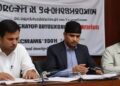 Sebuah ruangan konferensi pers dengan spanduk besar yang menulis 'KPK Gelar OTT di BNPB'. Empat pejabat tinggi BNPB sedang dibawa pergi oleh petugas KPK yang memakai pakaian formal, dengan kuncian tan