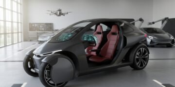 Sebuah kendaraan roda tiga modern terparkir di garasi, menampilkan desain ramping dan fitur terbaru. Kendaraan ini ditempatkan di tengah, dengan pandangan dekat pada dashboard dan kursi, menyoroti ino