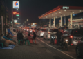 Antrean panjang kendaraan di SPBU di Bali dengan warga bermalam di trotoar, lampu malam menyinari antrian yang mengular, menunjukkan kelangkaan BBM meskipun stok klaim aman