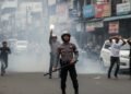 Peringatan Hari Bhayangkara 76 Tahun, Wali Kota Makassar Raih Penghargaan Dari Kapolda Sulsel Sebuah jalan di Makassar yang ramai dengan orang-orang berlari dalam kepanikan. Asap dan debu naik dari tanah. Seorang petugas kepolisian, memakai helm dan memegang palu, berdiri di depan. Di belakang