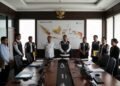 14 orang terduga korupsi dana siap pakai untuk bencana di BNPB ditempatkan di ruang konferensi, dihiasi dengan peta negara yang menunjukkan area rawan bencana, sementara petugas KPK melakukan operasi.