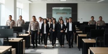 14 people are being escorted by law enforcement officers in a formal office setting. The background shows a modern office with desks and a conference room door. The scene conveys tension and importanc