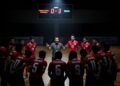 Medali Perak Pertama Indonesia dari Lifter Sri Wahyuni Suasana intens di lapangan futsal dengan skor 0-3 terpampang di papan skor. Timnas Futsal Indonesia berada dalam huddle, wajah mereka menunjukkan campuran antara keberanian dan kekhawatiran. Pelatih B