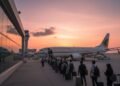 Pemkot Makassar Tampil di Expo Pengawasan Intern 2024 Sebuah terminal bandara yang ramai di sore hari, dengan pesawat Sriwijaya Air menjadi pusat perhatian di runways. Penumpang tampak memasuki pesawat dengan kantong-kantong mereka. Pesawat memiliki logo