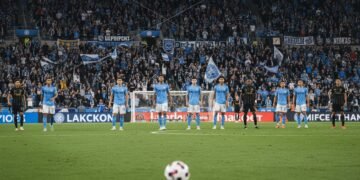 A busy Citi Field during a high-stakes MLS match between New York City FC and LAFC. The field is illuminated by spotlights, with passionate supporters creating a vibrant backdrop. The focus is on the