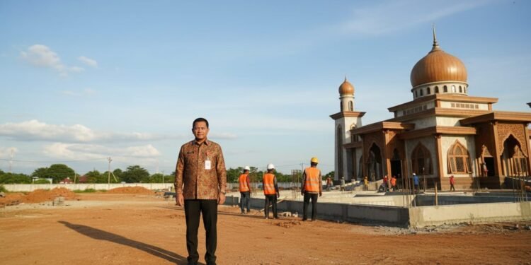 Gubernur Sulsel Beri Bantuan Rp 10 Miliar untuk Bangun Masjid di Asrama Haji Sudiang Gubernur Sulsel Budi S. berdiri di depan fondasi masjid baru di Asrama Haji Sudiang. Terlihat pekerja dengan jaket keselamatan berwarna oranye di latar belakang. Masjid memiliki desain yang mencermink