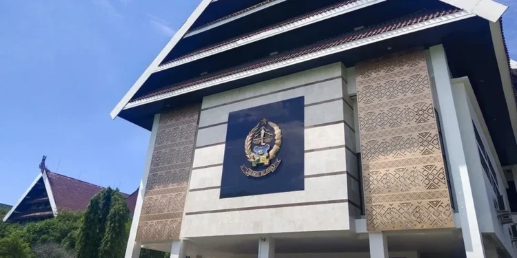 Gubernur Budi S. menghadiri parade sehat dan kirab swasembada pangan di Makassar, diiringi warga yang bersemangat dan bendera berwarna-warni. Latar belakang menampilkan campuran rumah tradisional dan
