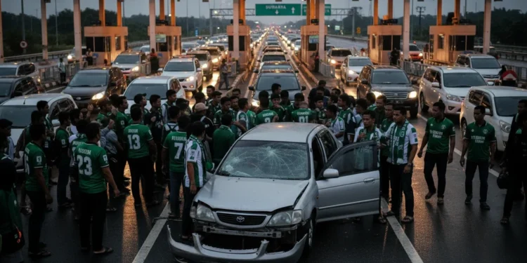 Kronologi Kecelakaan Rombongan Suporter PSS Sleman di Tol Madiun Sebuah adegan yang menunjukkan momen tegang di sebuah plazas jalan tol. Sebuah grup besar orang, yang kemungkinan adalah penggemar PSS Sleman, berkumpul di sekitar sebuah kendaraan yang rusak. Bagian