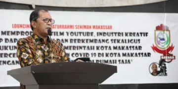 Sebuah studio modern dengan kaca besar dan sistem pencahayaan canggih. Dalam studio tersebut, ada sebuah laboratorium teknologi terkini yang penuh dengan peralatan high-tech dan layar yang menampilkan