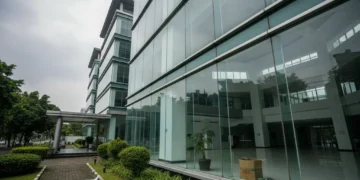 The image shows the Ministry of Women's Empowerment and Child Protection with its modern glass facade, surrounded by greenery. Inside, the atrium is bright and open, but the overcast sky and the build