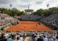 Pemenang Makassar Half Marathon 2016 The image shows the Roland Garros Stadium in Paris, France, with Court Philippe Chatrier and vibrant red and white flags. The atmosphere is filled with excitement for the upcoming French Open tennis t