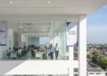 The image shows the main building of the Regional Office of the Directorate General of Civil Aviation (Ditjenpas) in Makassar, Sulsel, with a modern white facade and official logo. Inside, the office