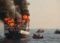 A burning KMP Batu Mandi in Selat Sunda with passengers being evacuated, dramatic lighting, rescue boats approaching, editorial photojournalism style
