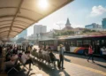 Sebuah pemandangan stasiun Transjakarta di Bandung pada hari Oktober yang panas. Stasiun ini berada di bawah atap besar dengan beberapa bangku untuk penumpang beristirahat. Matahari terik berada di la