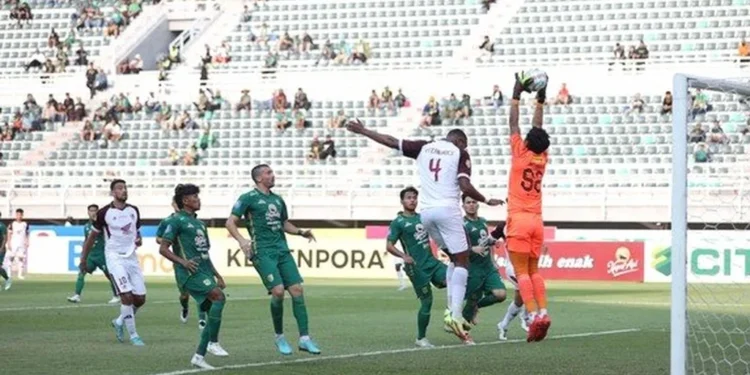 PSM Makassar vs Persebaya 1-0: Drama Penalti dan Kegagalan Alex Martins The main stadium of PSM Makassar is shown with its modern architecture and vibrant green field. The stadium is filled with excited fans, while Persebaya supporters are seen in the opposing section. Th
