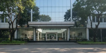 The main building of BMKG in Jakarta, Indonesia, with a modern glass facade and a prominent logo of a globe and wave, symbolizing meteorology, climatology, and geophysics. The interior is bright and o