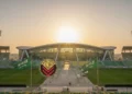 Hakim MK Bertanya soal Ijazah Gibran, Fokus Transparansi Data Pendidikan Al Qadisiyah's grand stadium with its modern architecture, surrounded by green fields and stands, under a warm golden sunset, adorned with the Saudi Arabian flag and the club's emblem, symbolizing the