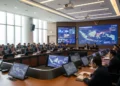 A modern conference hall with diplomats and officials from Indonesia and seven other nations discussing strategies to combat cross-border terrorism and cyber threats. The hall is equipped with advance