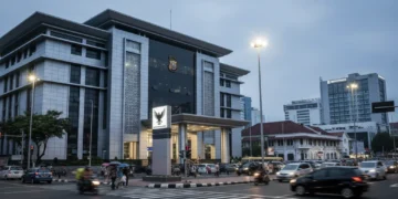 Tiga pria di Makassar ditangkap karena promosi judi online yang menghasilkan laba sebesar Rp 1,3 Miliar. Latar belakang berupa bangunan Polres Makassar dengan desain modern dan cahaya lampu jalan yang