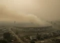 Hakim MK Bertanya soal Ijazah Gibran, Fokus Transparansi Data Pendidikan A dense haze covers the city of Palangka Raya, with the Merdeka Stadium partially obscured by the smoky atmosphere. The surrounding residential areas appear dilapidated and distressed, reflecting the