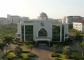 Sidang Senat Terbuka Luar Biasa Dies Natalis UNM ke-55 A grand entrance of the University of Muhammadiyah Makassar main campus with a modern blend of traditional and contemporary architectural elements, featuring a large glass window and a prominent dome.