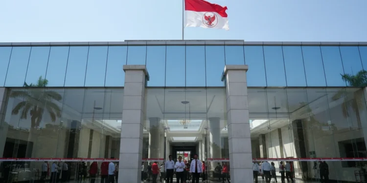 PSI Tanggapi Desakan Guru Besar agar Gibran Mundur, Singgung MK The main building of PDI-P is shown with its red and white flag, modern glass facade, and grand entrance. The interior is bright and spacious, with officials and supporters inside. The building is set