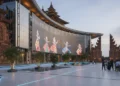 Keamanan Data: Pilar Utama dalam Ekosistem Teknologi Modern A grand venue for Gandrung Sewu 2026, featuring a modernist building with glass facades and metallic accents, surrounded by traditional Javanese architectural elements and digital screens. The interio