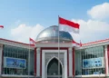The image shows the grand entrance of the PDIP headquarters with a red and white flag, modern architecture, and a bright interior filled with technology-themed exhibits, symbolizing PDIP's commitment