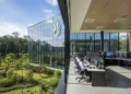 PTPN IV PalmCo headquarters, a modern building with large glass windows and a green landscape, featuring an advanced Early Warning System (EWS) control room and well-trained security personnel.