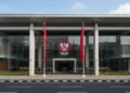 Unismuh Makassar Diserang OTK, Dua Mahasiswa Terluka Akibat Pukulan dan Panah PDIP's main building in Jakarta with a sleek glass facade and the party's emblem on the entrance. People in formal attire are gathered inside, ready for a dialogue on the tindak lanjut of the MK's dec