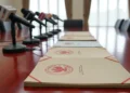 APBN 2026 ‘Survival Mode’: Menteri Keuangan Purbaya Tegaskan Nol Toleransi untuk Inefisiensi dan Kebocoran Foto dokumentasi resmi pemerintah Indonesia dengan segel merah di atas meja kayu jati berkilau disertai deretan mikrofon stasiun televisi sebagai simbol pers.