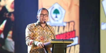 Foto dokumentasi meja rapat resmi dengan dokumen bersegel merah dan mikrofon penyiar di atasnya.