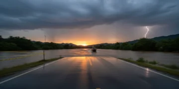 Jalan aspal genangan air dengan hujan deras memantulkan awan badai dramatis saat senja; perahu penyelamat berwarna oranye melintas di tengah banjir, garis polisi kuning membentang di tepi jalan, kilat