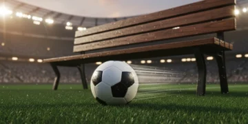 Bola sepak profesional bersandar pada rumput hijau stadion yang basah dengan pencahayaan dramatis malam hari dan latar belakang lampu tribun yang kabur; tidak ada pemain atau logo terlihat.