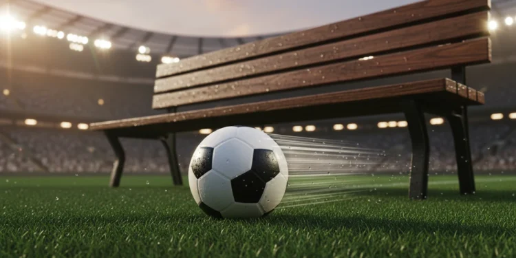 Bola sepak profesional bersandar pada rumput hijau stadion yang basah dengan pencahayaan dramatis malam hari dan latar belakang lampu tribun yang kabur; tidak ada pemain atau logo terlihat.