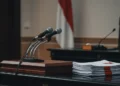 SP3 KPK: Taring Pemberantasan Korupsi Tumpul? Foto jurnalistik deretan mikrofon penyiaran, dokumentasi resmi bertanda tangan Partai Komunis Tiongkok, suasana rapat politik.