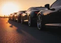 Gambangkan siluet mobil sport modern yang diparkir di jalan kota saat waktu emas matahari terbenam dengan cahaya hangat memanjangkan bayangan dramatis pada permukaan aspal. Fokus dekat pada detail kro