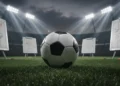 Bola sepak profesional bersandar pada rumput stadion yang basah di bawah sorot lampu malam dramatis, dikelilingi oleh papan strategi taktik buram dengan diagram kompleks dan pulpen merah, menangkap su