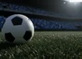 Piala Asia 2023: 1-0 Indonesia Menundukkan Vietnam, Membuka Peluang Lolos 16 besar Bola sepak profesional bersandar di rumput basah bawah sorot lampu stadion dramatis pada malam hari dengan latar belakang kursi kosong yang buram menciptakan suasana ketegangan tanpa pemain atau logo